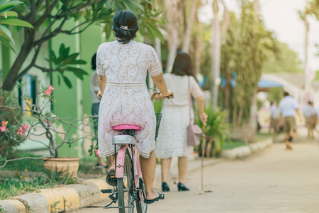 Back view of female teacher rides bicycle to teach students at classroom.の写真素材