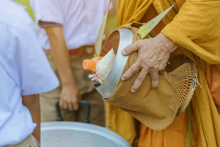 Teachers and students together make merit to give food offerings to a Buddhist monk on important religious days at school.の写真素材