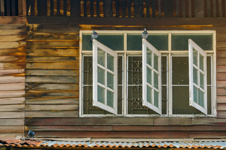 Pigeons on old wooden window of the former wooden house.