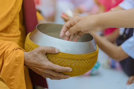 Teachers and students together make merit to give food offerings to a Buddhist monk on important religious days at school.の写真素材