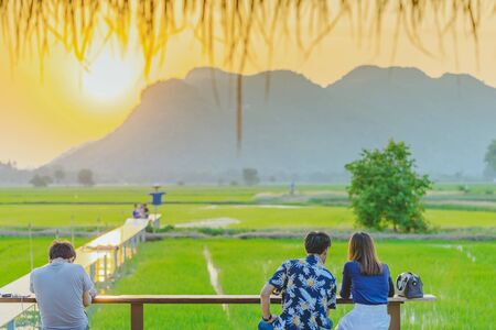Back view of people sit for resting and waiting for time to take photos of the sunset on the...