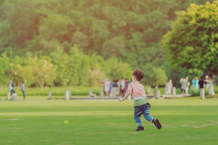 Kid enjoy to playing with little ball on green fieldの写真素材