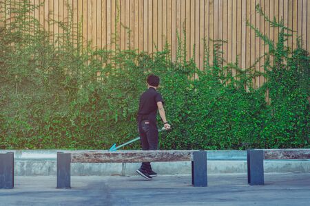 Young man cleaning fountain pool from fallen leaves with net