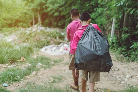 Male Students help to remove rubbish from the classroom to pile waste. Selective focus on black garbage bag.の写真素材