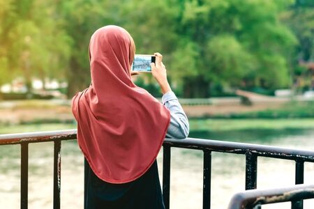 Back view of Muslim woman relax and admire the beautiful scenery in the evening on The Bridge of the River Kwai in Kanchanaburi, Thailand.の写真素材