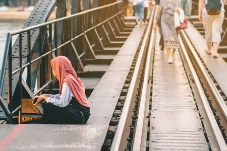 Muslim woman relax and admire the beautiful scenery in the evening on The Bridge of the River Kwai in Kanchanaburi, Thailand.の写真素材