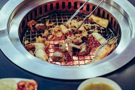 People grilling meat on a smokeless barbecue grill in a restaurant.の写真素材