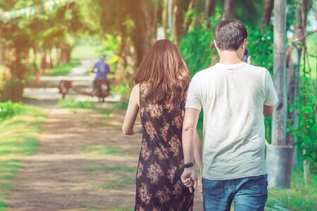 Couple walking and taking photos under the pine trees in the public park.の写真素材