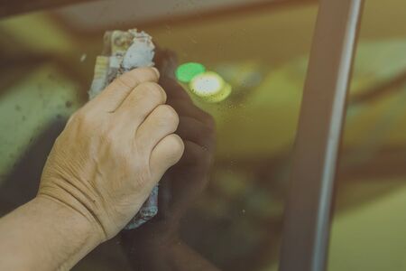 Close up to hand of male worker use wet newspapers to clean the glass part of the car. Selective focus on hand.の写真素材
