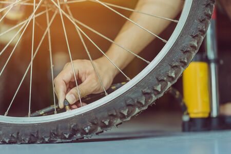 Close-up of a young man prepare to pumping the old bicycle wheel in his home. .の写真素材