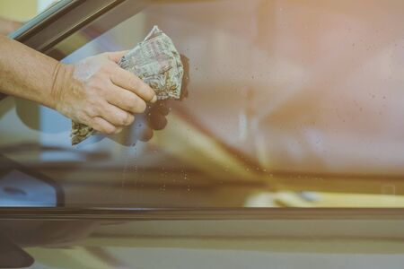Close up to hand of male worker use wet newspapers to clean the glass part of the car. Selective focus on hand.の写真素材