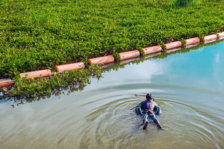 Hunter fisherman with a speargun on a life ring looks under the water in search of fish in the evening.の写真素材