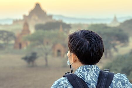 Back wiew of tourists admire and take photography while the sun sets at the ancient pagoda temples in the asian historic heritage city Bagan, Myanmarの写真素材