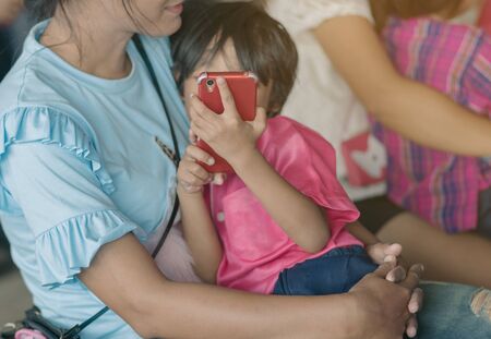 Mom is enjoying time with her daughter while she is using smartphone.の写真素材