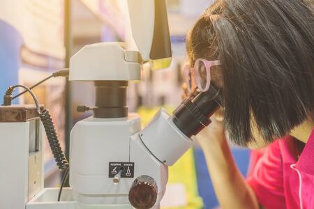 A Girl take off glasses for learn to use microscope in the science lap at school. Learning and...