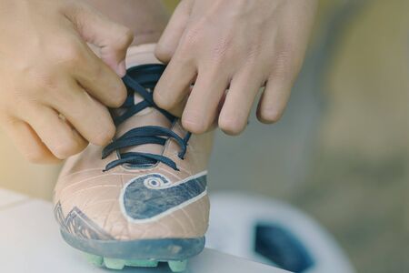 Close up to Young man sit to tying studded laces before play soccer.の写真素材