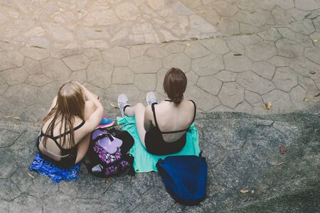 Top view of Female tourists in black swimming suit sit and relax beside the path after playing in the Erawan waterfall in Kanchanaburi, Thailand.の写真素材