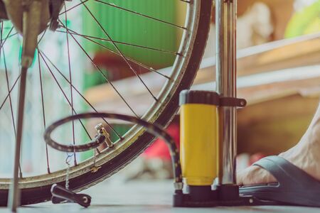 Close-up of a young man prepare to pumping the old bicycle wheel in his home. .の写真素材
