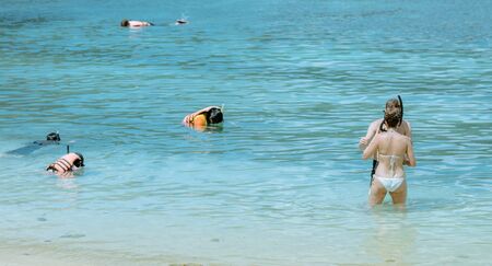 A gentleman helped wear glasses for his lover before snorkelling to see the beautiful coral in the sea.の写真素材