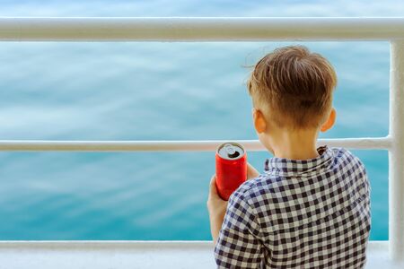 Asian boy stands on baluster of ferry for relaxing and look at the ocean and islandの写真素材