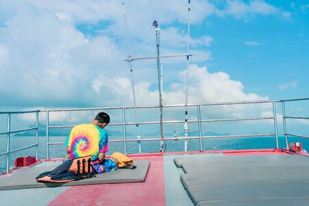 Tourists relaxing on boat deck and use smartphone on hot sunny day.