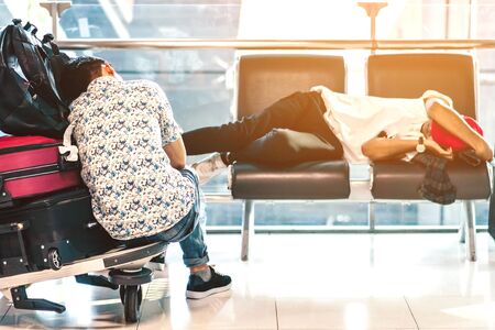 Tired passenger napping on a trolley while waiting for boarding in the in airport terminal.の写真素材