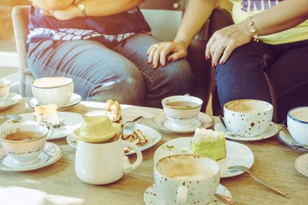 Happiness female friends meeting and drinking tea or coffee with cakes together at cafe in the afternoon. People, leisure and communication concept. Selective focus.の写真素材
