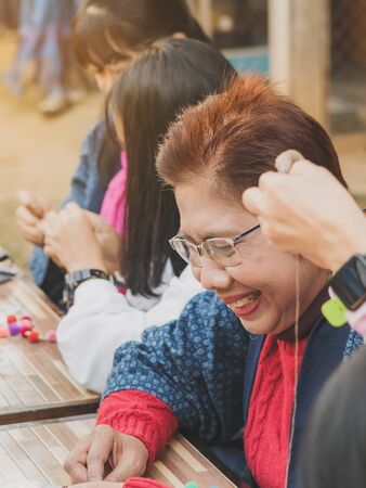 LAMPHUN THAILAND - DECEMBER 12 :  Unidentified Thai female tourists learn to make a necklace from a yarn ball on December12,2019 at Karen village in Lamphun, Thailandのeditorial素材