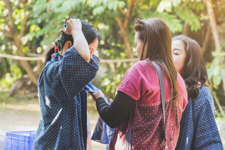 LAMPHUN THAILAND - DECEMBER 8 :  Unidentified female tourist helps her mother to tie a scarf on December 8,2019 at Karen village in Lamphun, Thailand.のeditorial素材