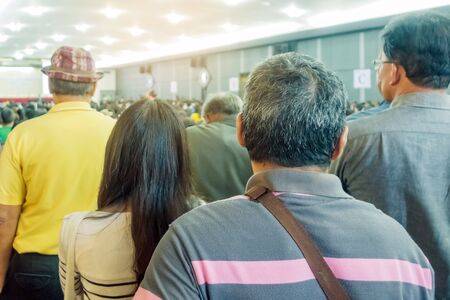 Backside view of spectators standing in a gathering in the back of auditorium full of people. Selective focus.の写真素材