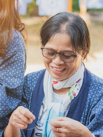 LAMPHUN THAILAND - DECEMBER 12 :  Unidentified Thai female tourists learn to make a necklace from a yarn ball on December12,2019 at Karen village in Lamphun, Thailandのeditorial素材