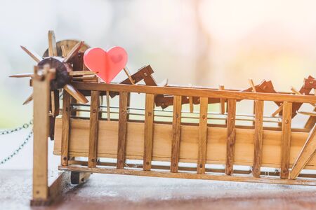Red heart shaped candle on a turbine baler model made of wooden on table. Valentine day and love concept.の写真素材