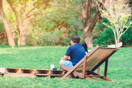 Happiness couple on a summer holiday sitting on  garden chairs to relax in the public park.の写真素材