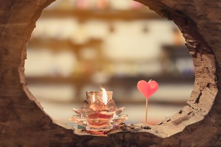 A red heart shaped candle and candlelight in small glass cup to decorate on Valentine's Day. A valentine's day background.の写真素材