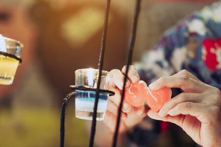 A red heart shaped candle in a woman's hand with candlelight in many small glass cups. A valentine's...