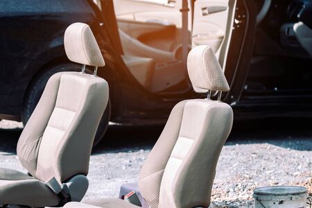 Cream-colored car seats removed from the black car for sun exposure and cleaning in open air.の写真素材
