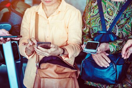 Elderly women learn how to use applications related to language translation from young men. While traveling abroad at the airport.の写真素材