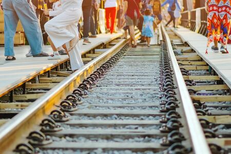 Tourists walk across across rail train tracks from side to another side while visiting The Bridge Over the River Kwai in Kanchanaburi, Thailand.の写真素材
