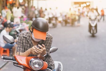 Male tourist parked a motorbike on the roadside to use his smartphones to find routes in the city.の写真素材
