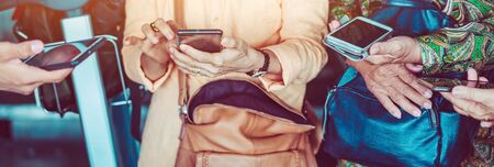 Elderly women learn how to use applications related to language translation from young men. While traveling abroad at the airport.の写真素材