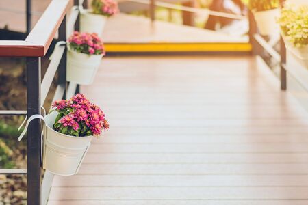 Beautiful artificial flowers in small pots hanging to decorate a railing walk for beauty on the pathway in public gardens. Selective focus.の写真素材