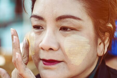 MANDALAY-Myanmar, January 20, 2019 : Female tourist guide paints tanaka powder on female tourist face while traveling on boat on january 20,2019 in Mandalay, Myanmar.のeditorial素材