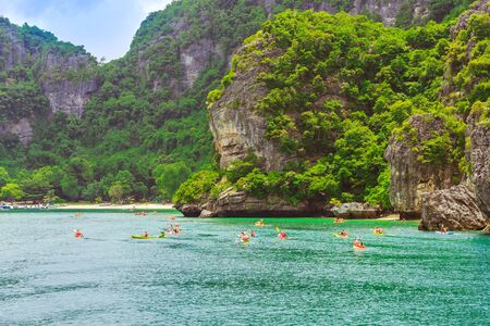 ANG THONG MARINE PARK, SAMUI, THAILAND - OCTOBER 13,2019 : Tourists kayaking in blue Idyllic turquoise ocean to explore near the island with lush green jungle trees and limestone mountains at Ang Thong National Marine Park, Thailand.のeditorial素材