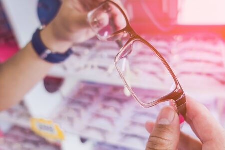 Hands of young man choosing new optical glasses in optician shop. Health care, eyesight and vision conceptの写真素材