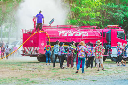 KANCHANABURI, THAILAND - APRIL 17, 2019: Unidentified Thai people in wet clothes fun with fire truck...
