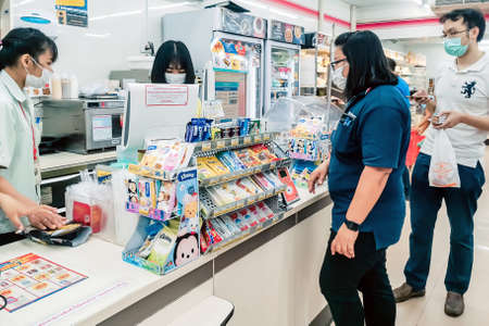 KANCHANABURI, THAILAND - MARCH 27,2020: Unidentified Cashier or 7-eleven staff and customers in...
