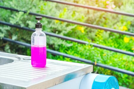 Pink alcohol gel bottle or antibacterial soap sanitizer on aluminum sinks in garden, Alcohol gel for cleaning hand to prevent the spread of germs and bacteria and avoid infections corona virus (covid-19)の写真素材