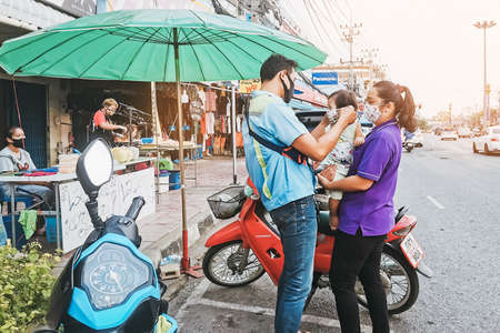 KANCHANABURI, THAILAND - April 15, 2020 : Unidentified dad puts on a protective medical mask to her...