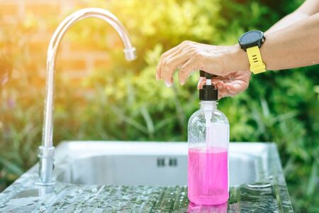 A woman washing hands from the tap with pink soap in a aluminium tub. Concepts of Flu virus, Covid-19 (Coronavirus disease). Selective focus.の写真素材
