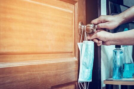 Two masks for lovers hanging on the bedroom door knob with alcohol gel to wash hands to prevent...